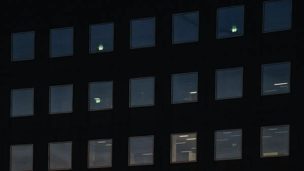 Office building facade at dusk with a few floors still lit