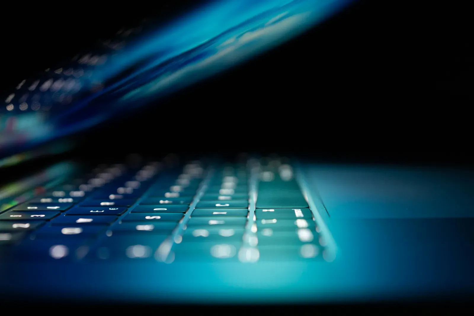 Laptop keyboard glowing in the dark during overnight manufacturing IT support