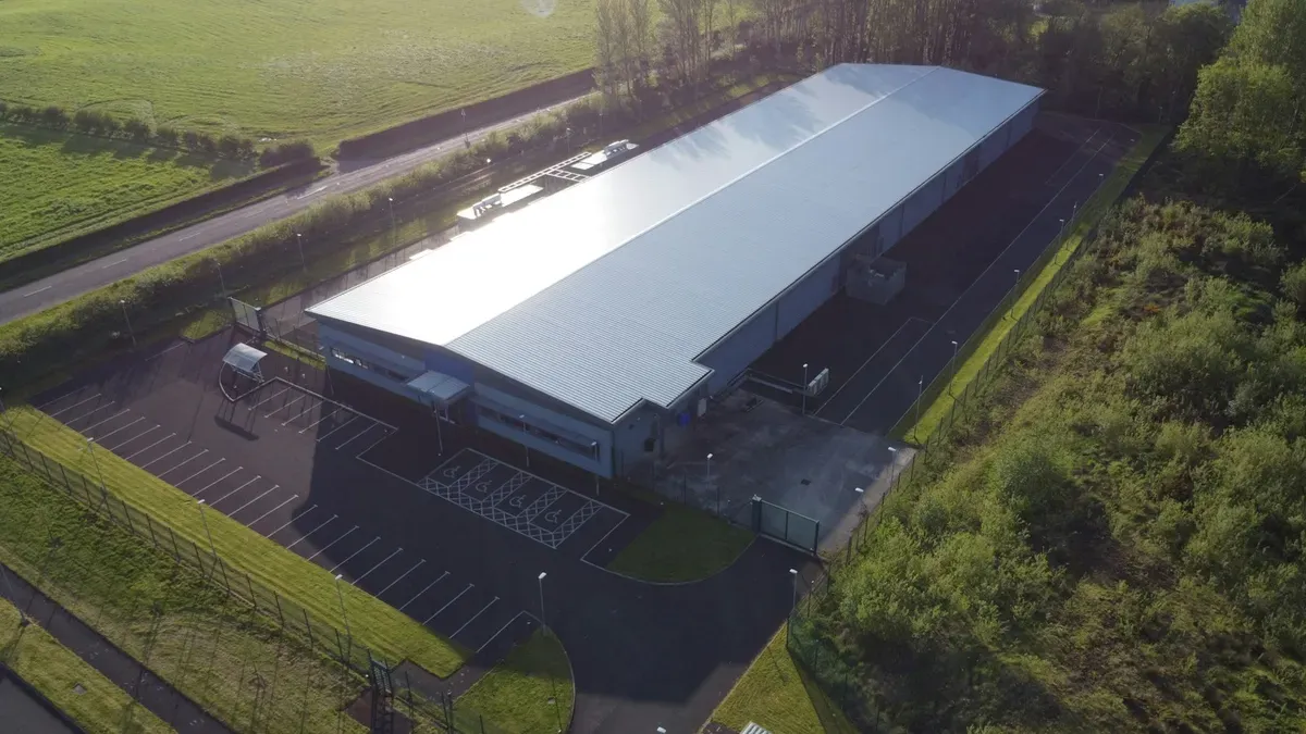 Aerial view of a single industrial building and its parking lot beside a rural road